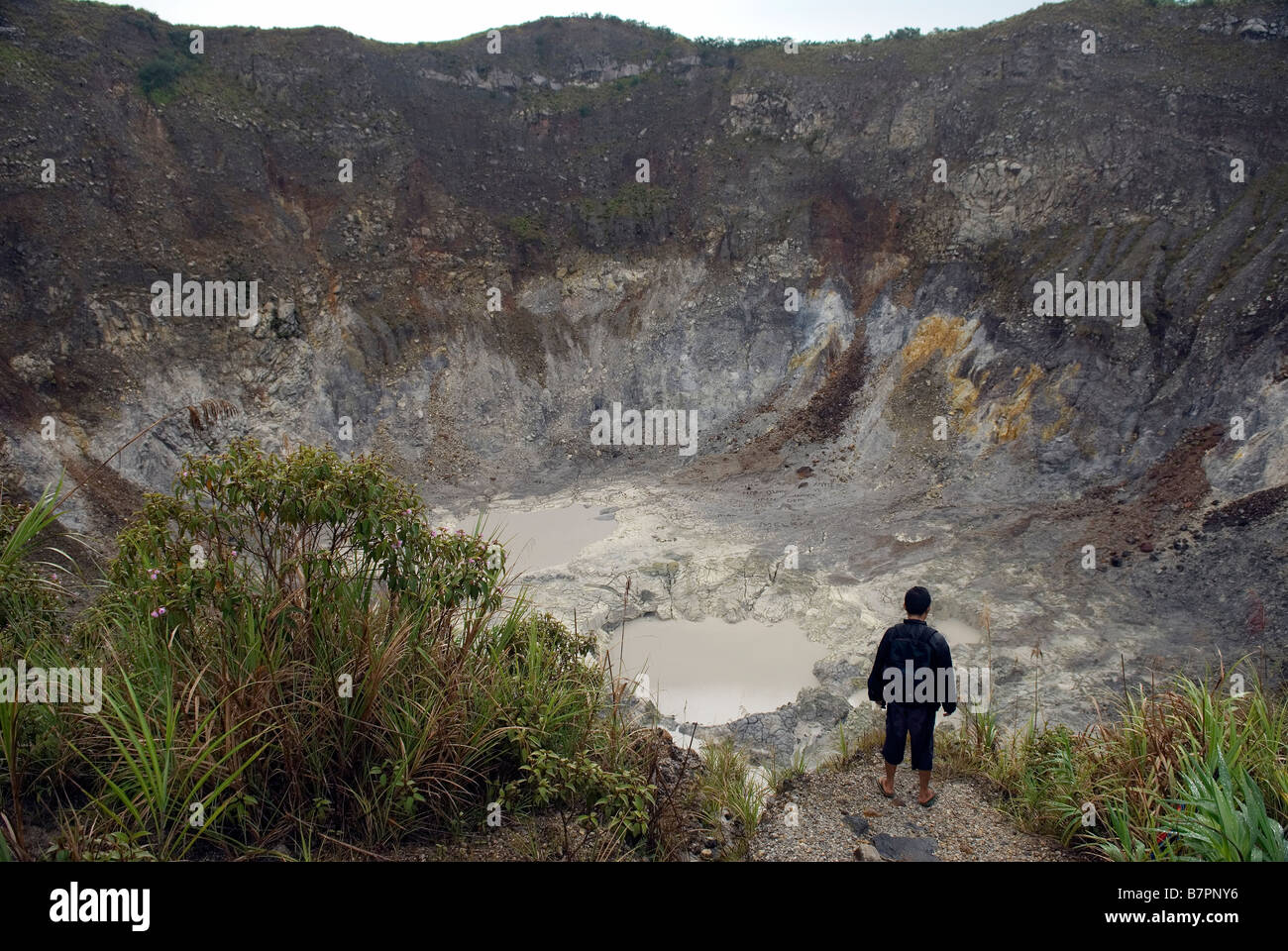 Sulawesi guide looks in the still steaming crater of Mahawu volcano. Stock Photo