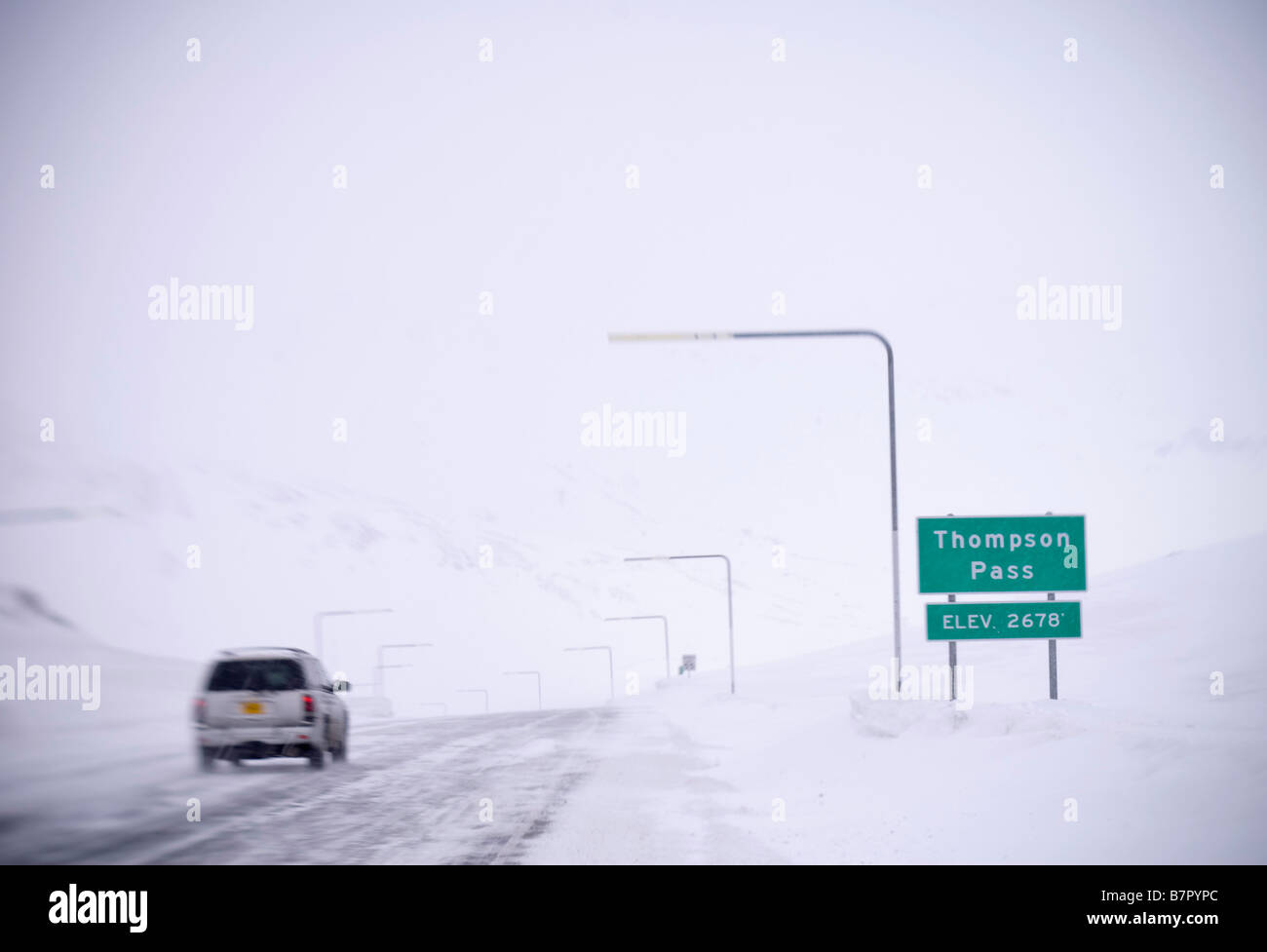 Vehicle drives on slick road in near whiteout conditions, Thompson Pass in Southcentral Alaska during Winter Stock Photo