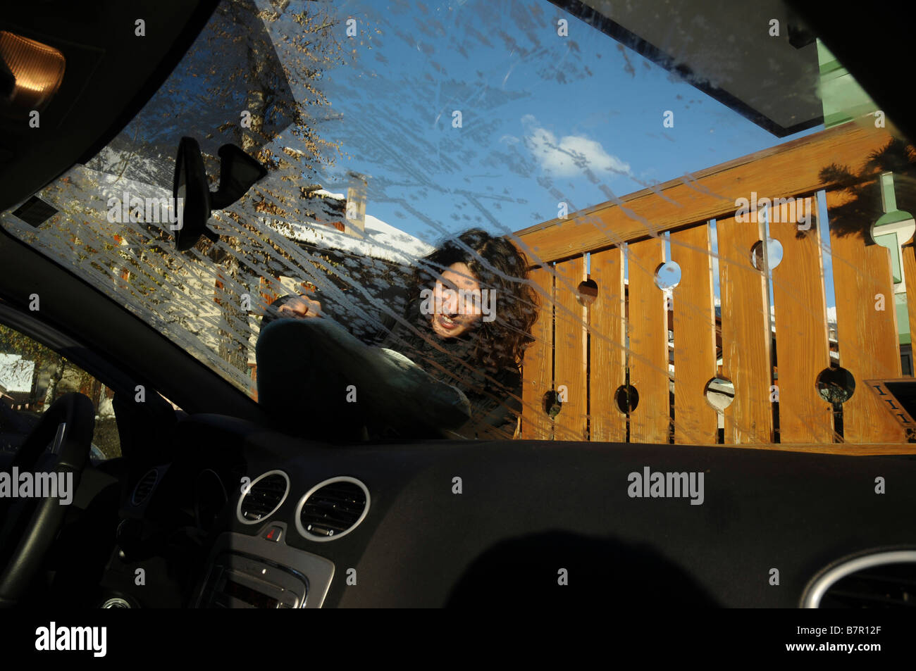 Italy The Dolomites Woman scraping ice off her car s windshield on a cold and frosty morning Model Release Available Stock Photo