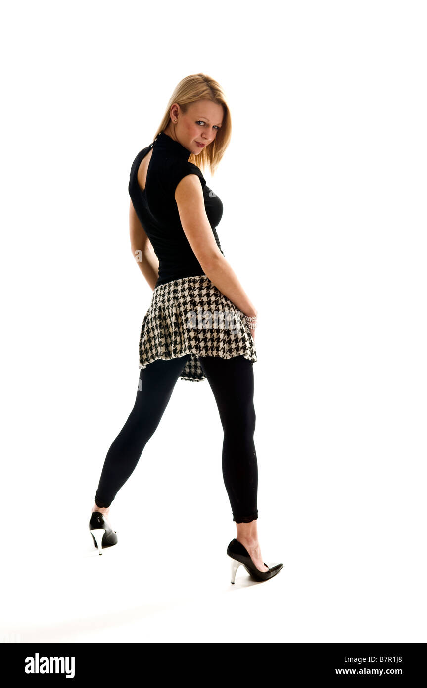 Young female model with blond hair standing full length looking to camera over her shoulder wearing black and white Stock Photo