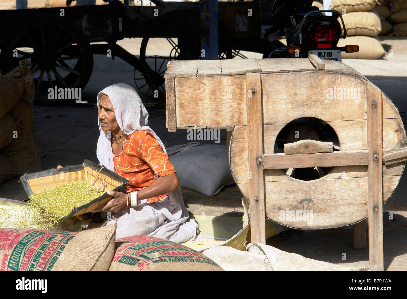 indian woman with traditional machinery and cereal crops in the market
