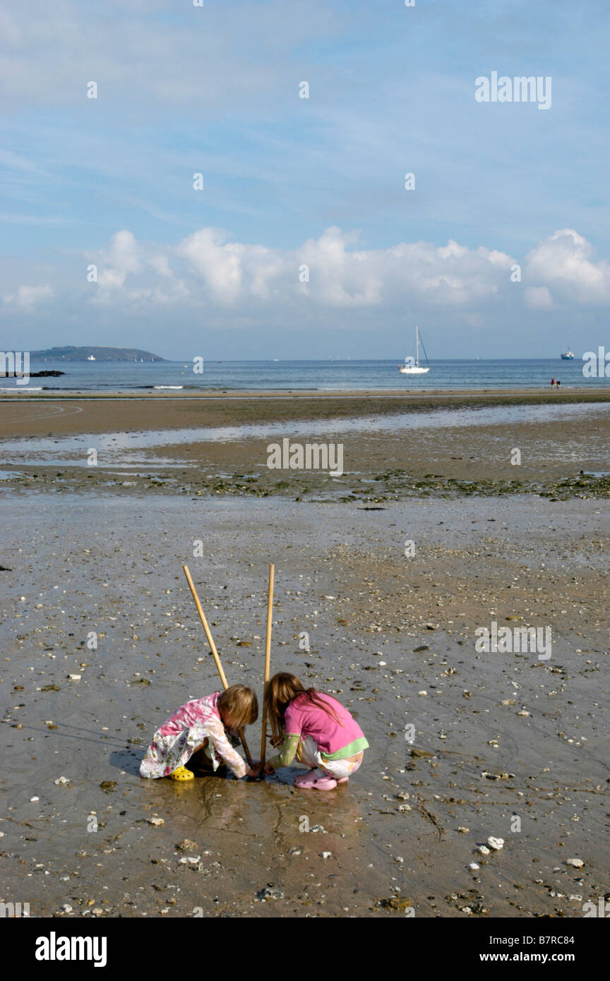 2 sisters on Maenporth a Cornish (UK) beach collecting shells, crabs etc Stock Photo