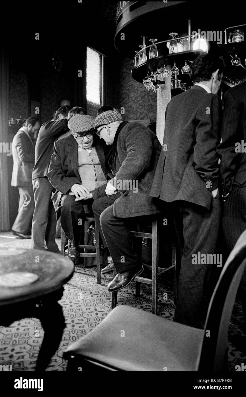 Two old men in cloth caps in conversation in their local pub Kentish Town London Stock Photo