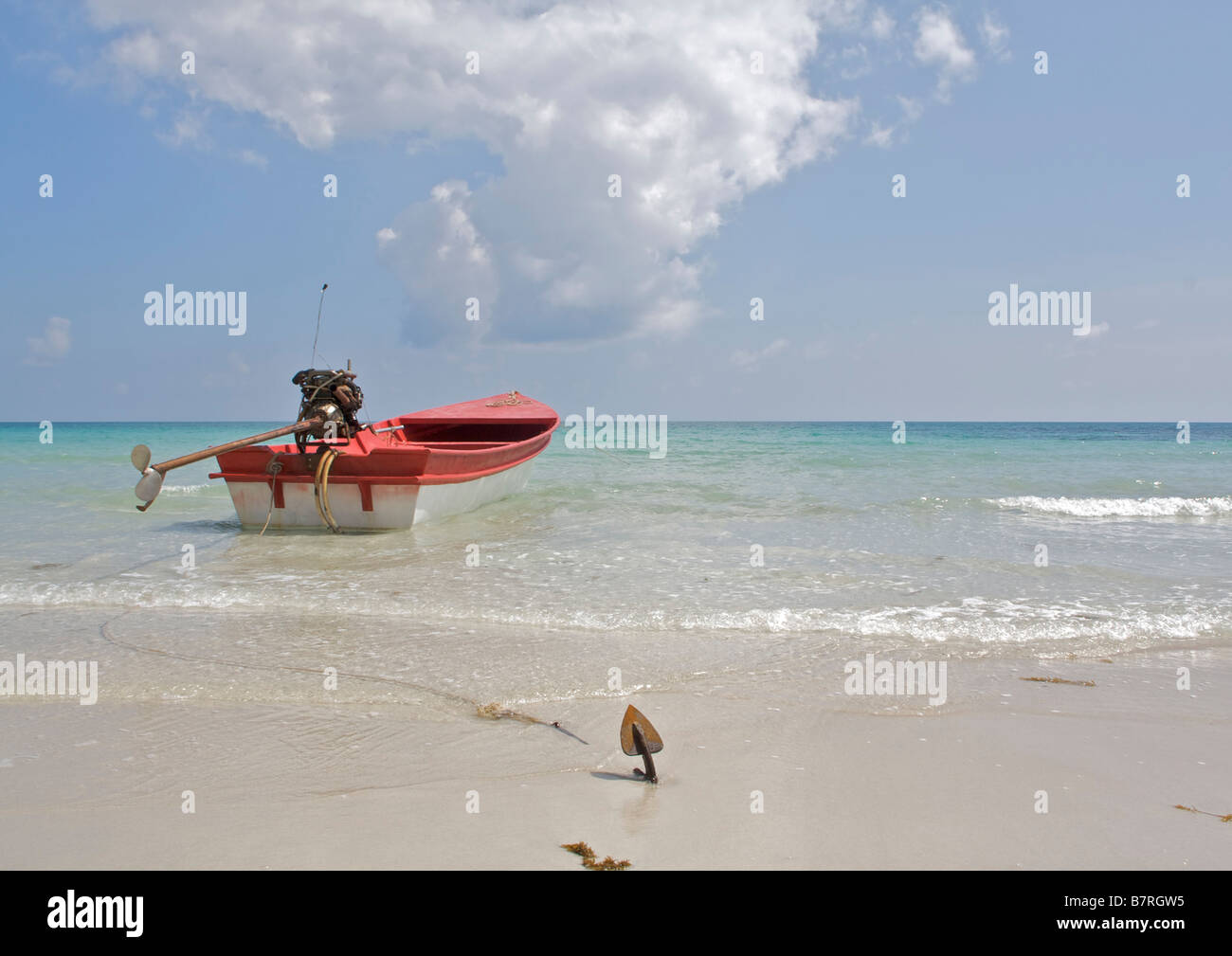 A long tail boat sits on the crystal clear waters of  Haad Rin Nok beach Koh Phangan Thailand under a blue sky Stock Photo