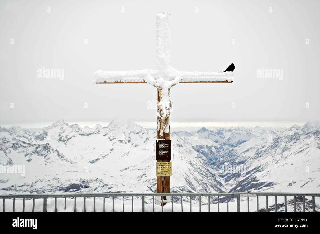 Snow covered Crucifix with crow on the Peak Kleines Matterhorn Stock Photo