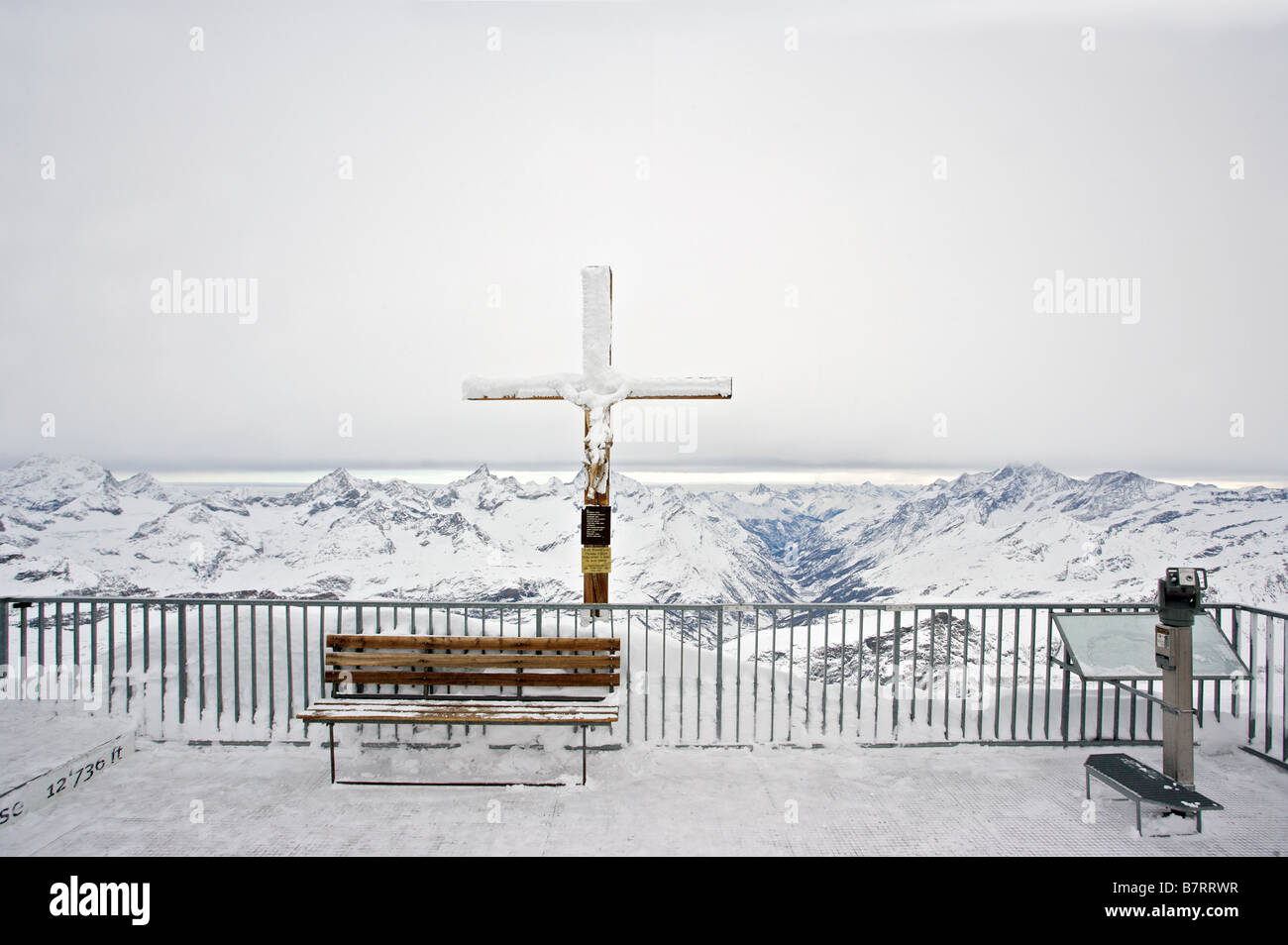 Snow covered Crucifix with crow on the Peak Kleines Matterhorn Stock Photo