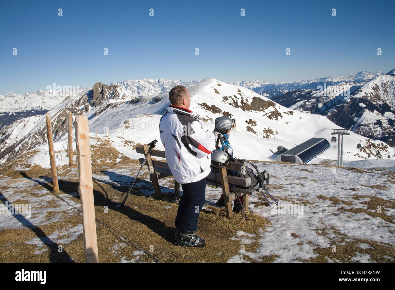 Pinzgau Region Austria EU January Male and female skiers at a viewpoint above Gipfelbahn gondola station taking in view to Alps Stock Photo