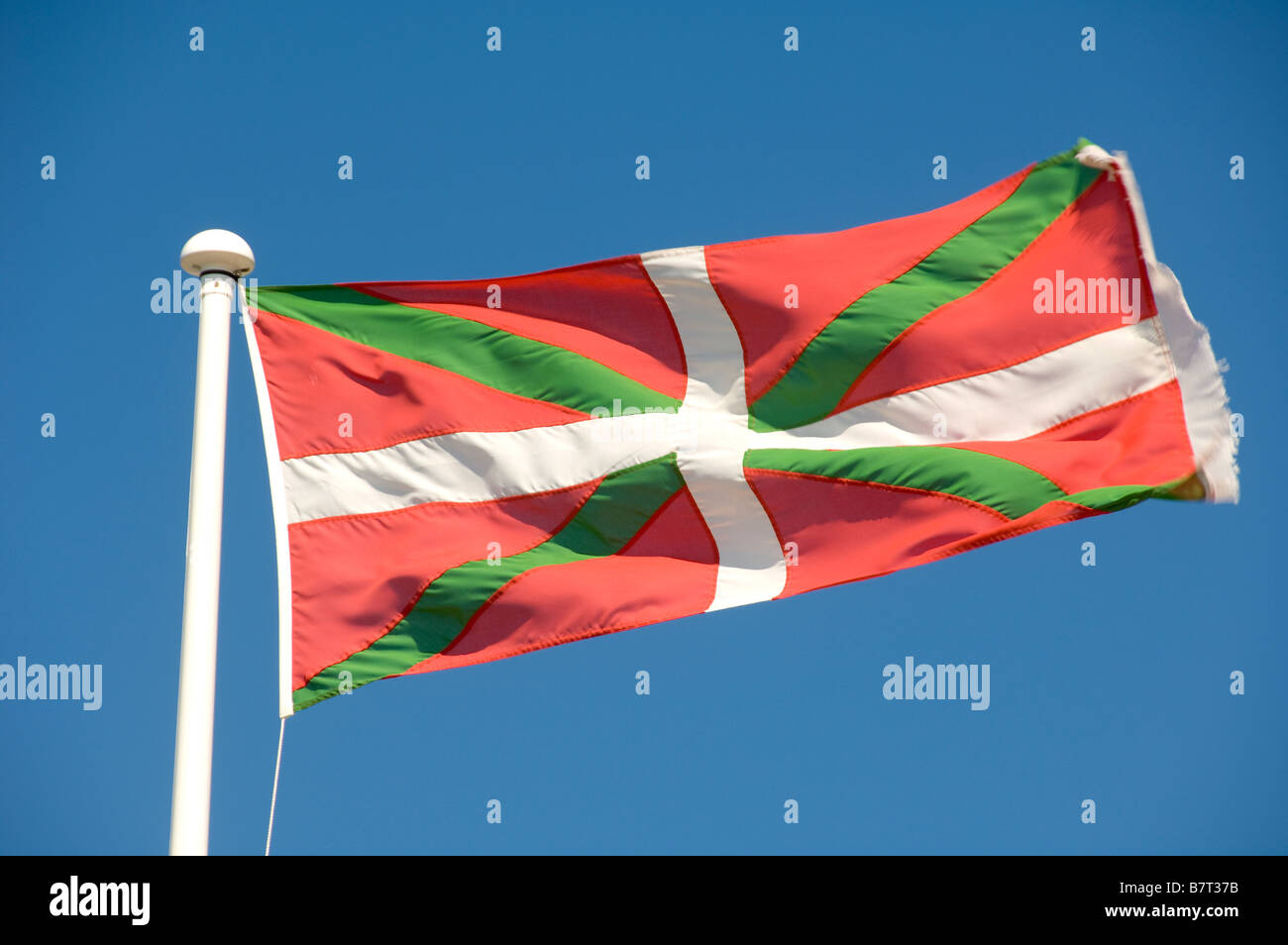 Basque Country flag flying from a white flagpole on a sunny day. Seen ...