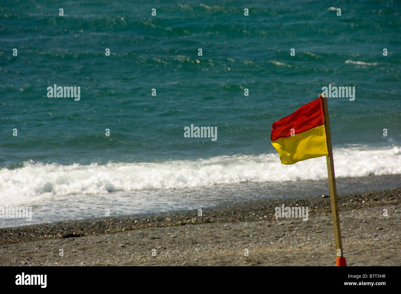 Red and yellow RNLI beach bathing flag on a UK beach indicating that it's safe to swim. Stock Photo