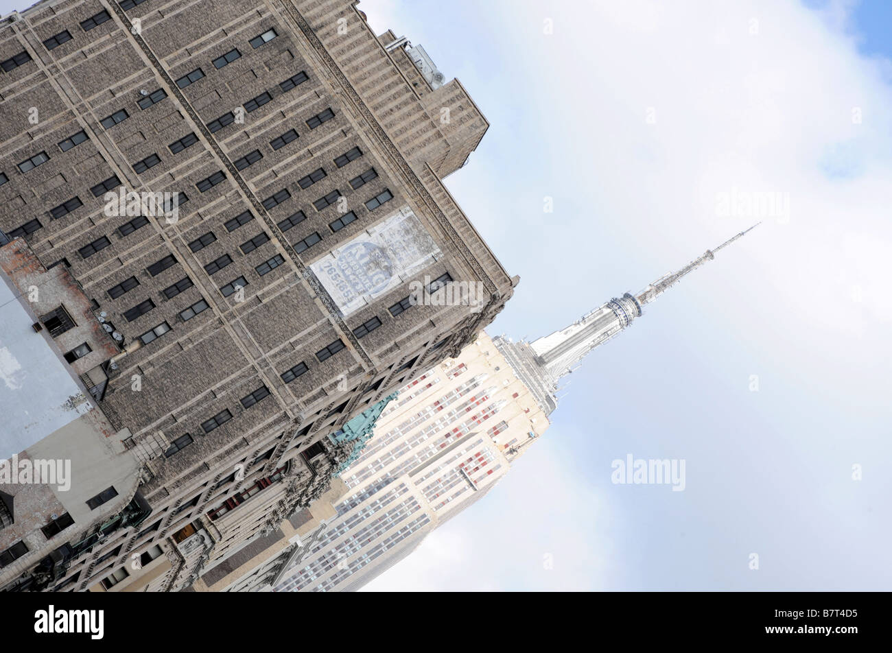 New York skyline - Empire State Building spire behind old skyscraper and blue sky Stock Photo