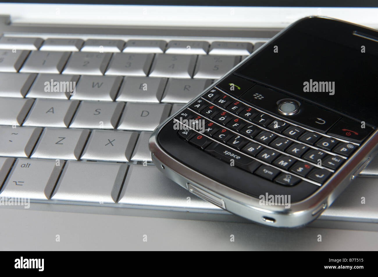 Blackberry smartphone on computer keyboard Stock Photo
