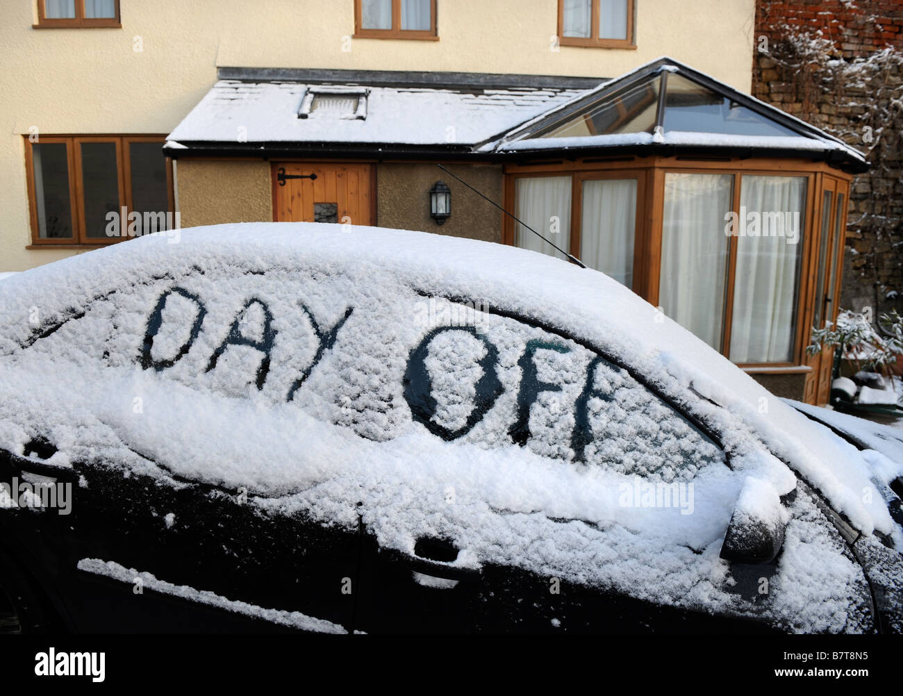 CAR PARKED ON A DRIVEWAY WITH WORDS DAY OFF WRITTEN IN SNOW SUGGESTING ABSENTEEISM FROM WORK DURING MODERATE WINTERY CONDITIONS Stock Photo