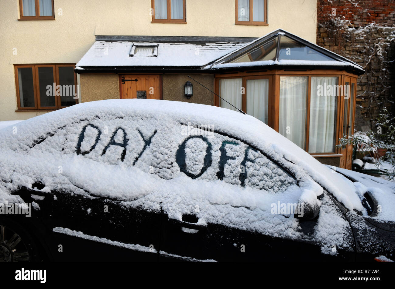 CAR PARKED ON A DRIVEWAY WITH WORDS DAY OFF WRITTEN IN SNOW SUGGESTING ABSENTEEISM FROM WORK DURING MODERATE WINTERY CONDITIONS Stock Photo