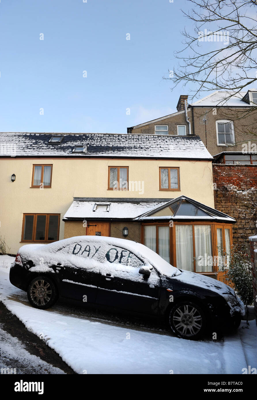 CAR PARKED ON A DRIVEWAY WITH WORDS DAY OFF WRITTEN IN SNOW SUGGESTING ABSENTEEISM FROM WORK DURING MODERATE WINTERY CONDITIONS Stock Photo