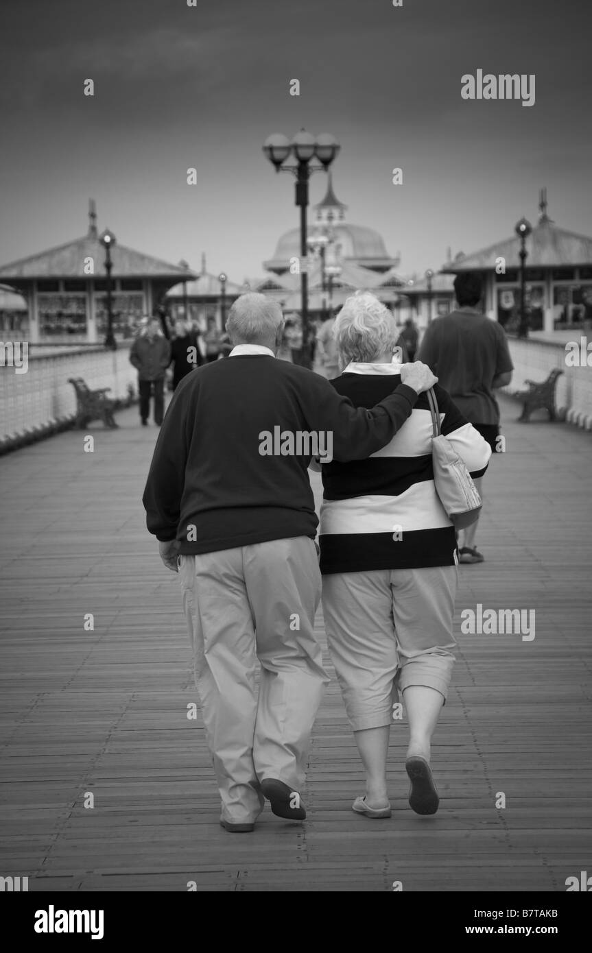 Rear view of mature caucasian couple walking along Llandudno pier. UK Stock Photo