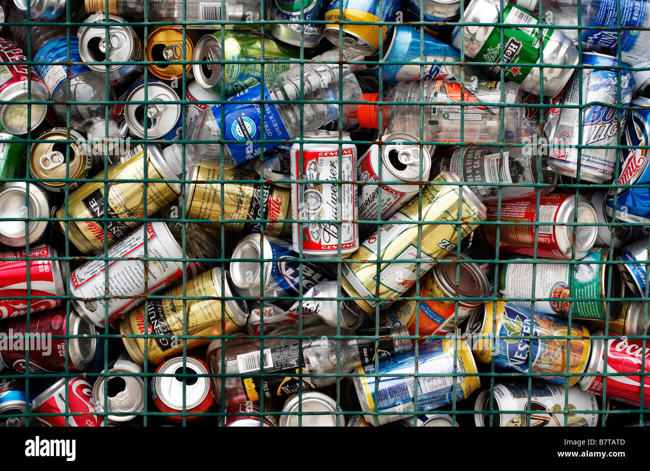 A large number of aluminum cans and plastic bottles destined for recycling in a wire mesh container. Stock Photo