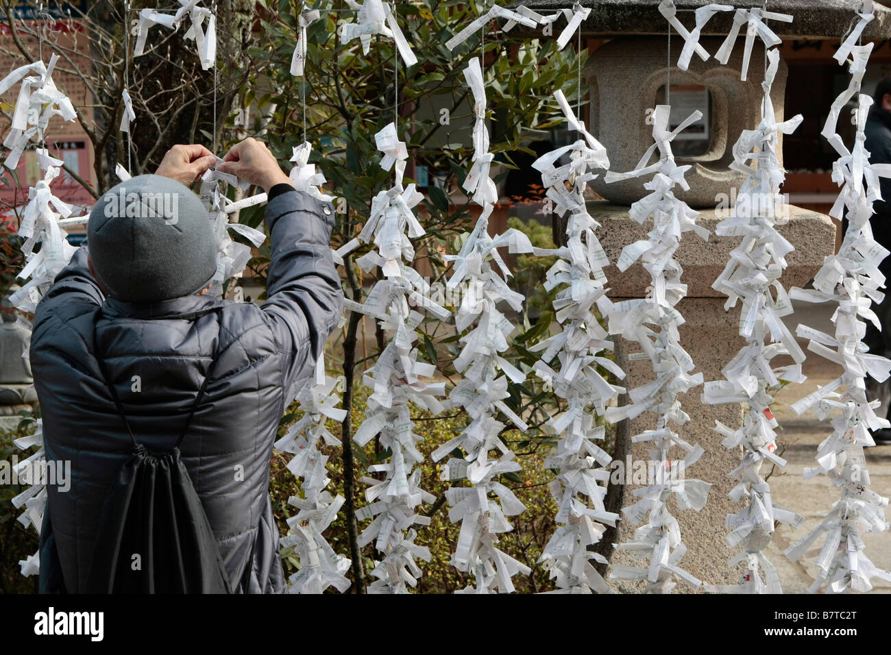 A man ties a note with a prayer message at the Daisho-In Temple on Miyajima Island near Hiroshima, Japan. Stock Photo