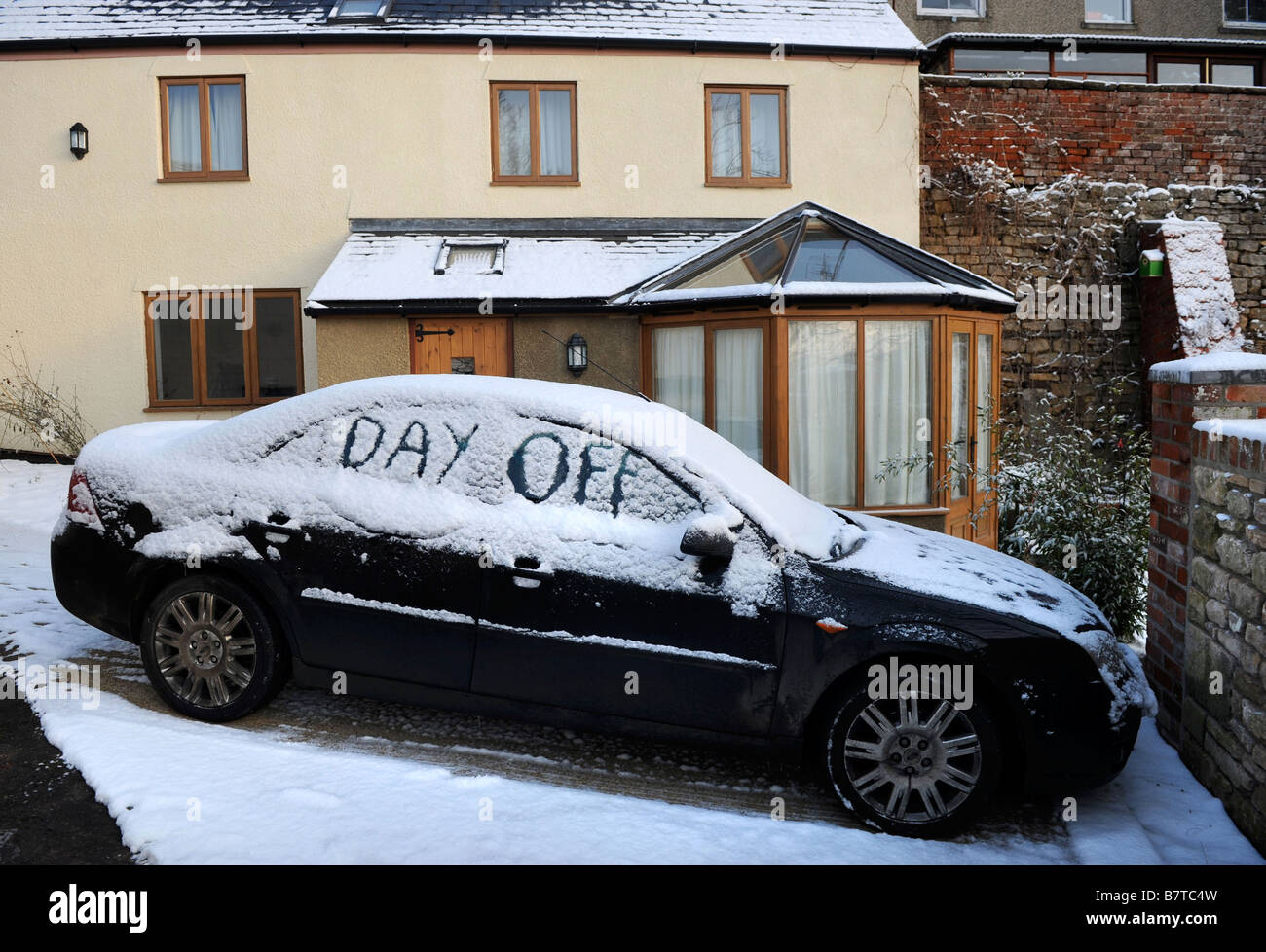 CAR PARKED ON A DRIVEWAY WITH WORDS DAY OFF WRITTEN IN SNOW SUGGESTING ABSENTEEISM FROM WORK DURING MODERATE WINTERY CONDITIONS Stock Photo