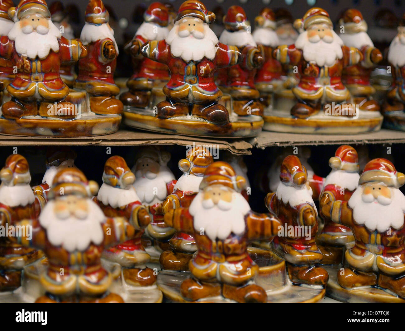 Santa Claus figures on display for retail sale on a cardboard shelf. Stock Photo