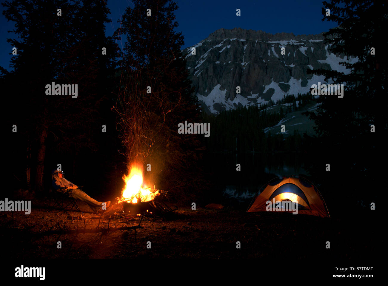 a man sits at a campsite at night in front of a campfire at alta lakes, colorado Stock Photo
