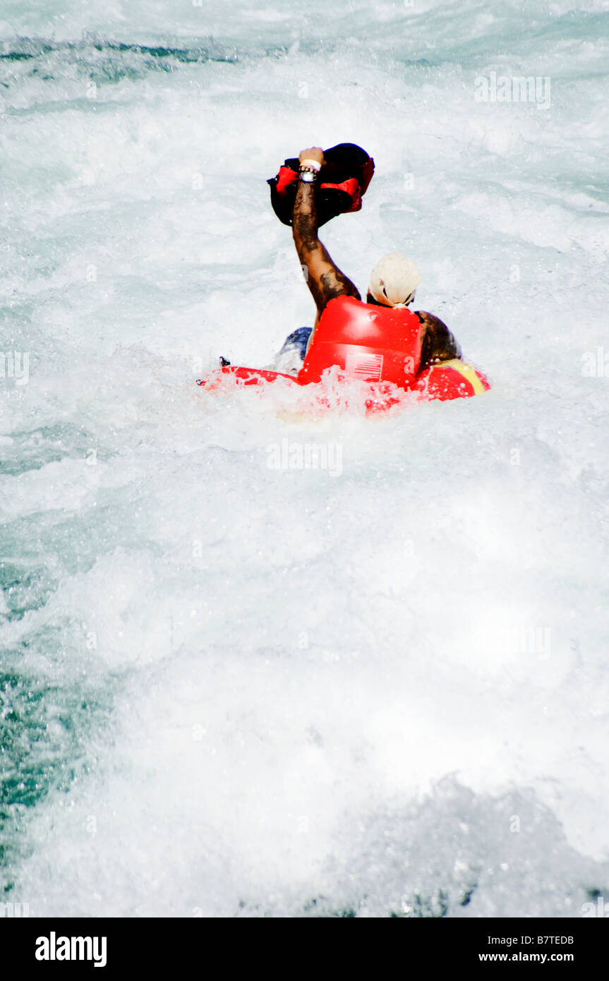 Man in innertube going over rapids and holding up his beer cooler on Guadalupe River in New Braunfels Texas Stock Photo