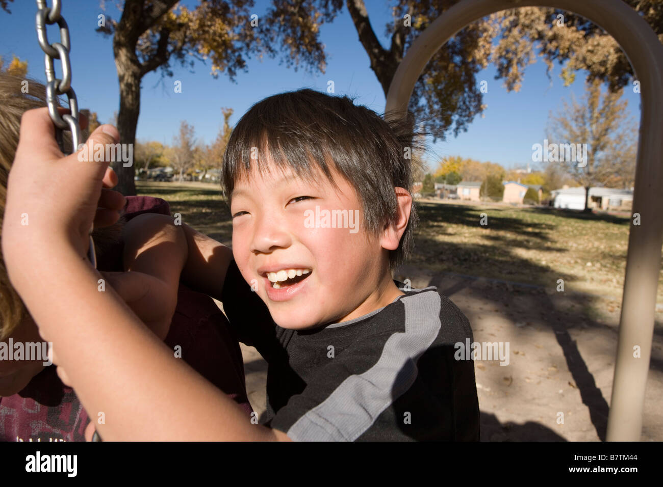 close up of happy nine year old japanese boy swinging on a tire swing at a public park Stock Photo