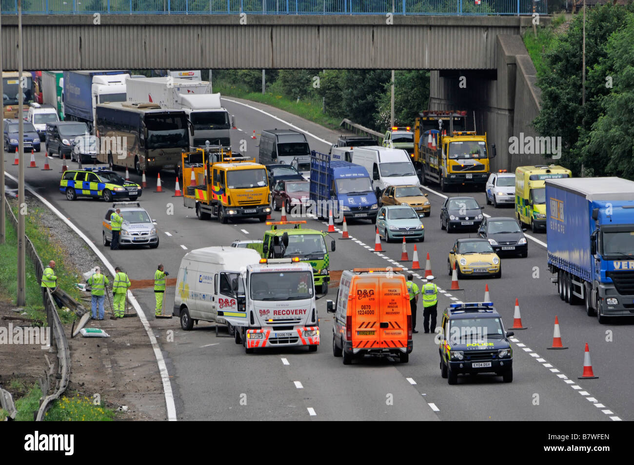 Aerial view M25 motorway queue of delayed slow moving car lorry truck traffic passing road traffic accident with police & recovery vehicles England UK Stock Photo