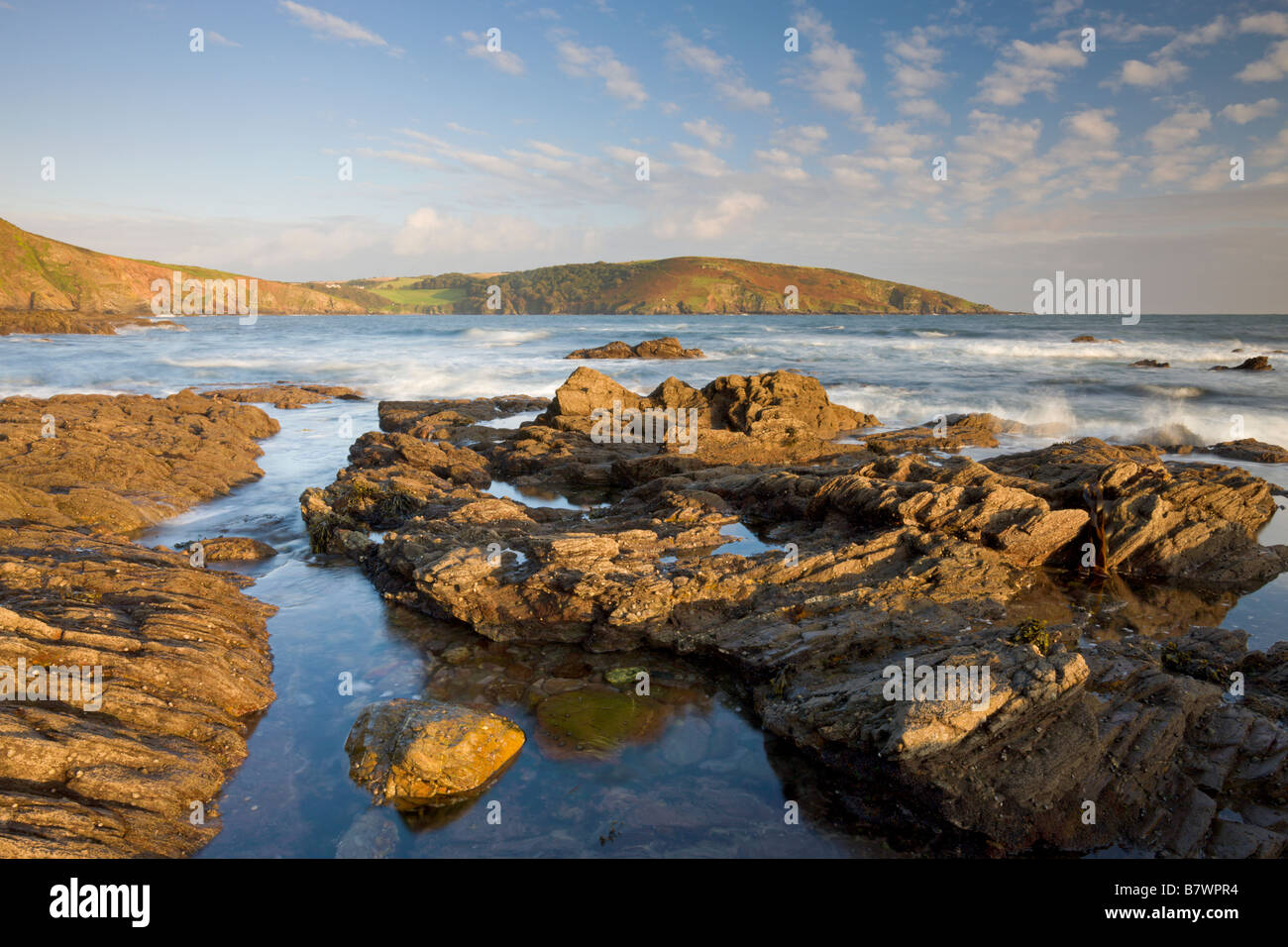 Evening sunlight bathes the rocky shores and cliffs golden at Wembury Bay in South Devon England Stock Photo