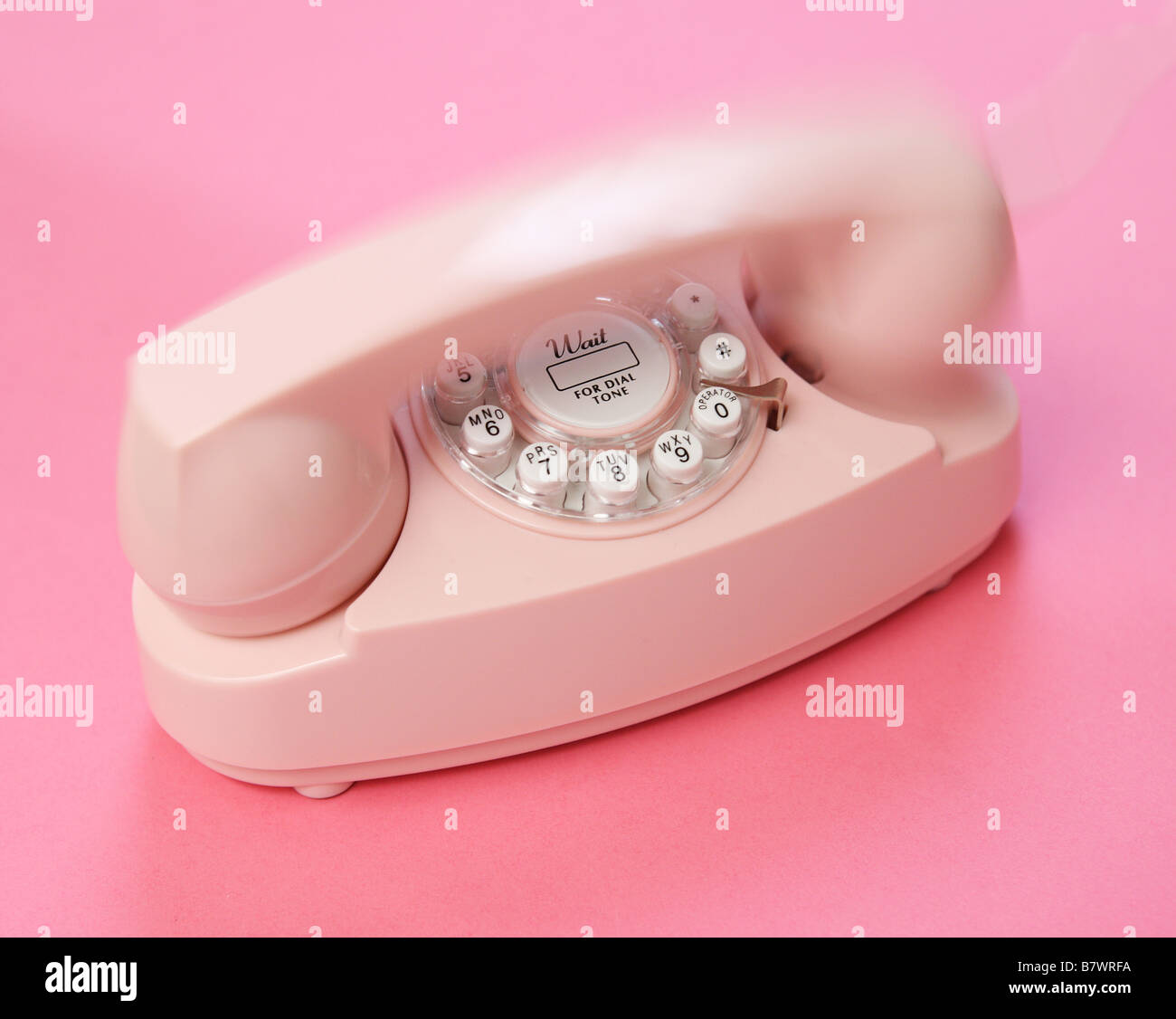a pink telephone on  a pink background appearing to ring Stock Photo