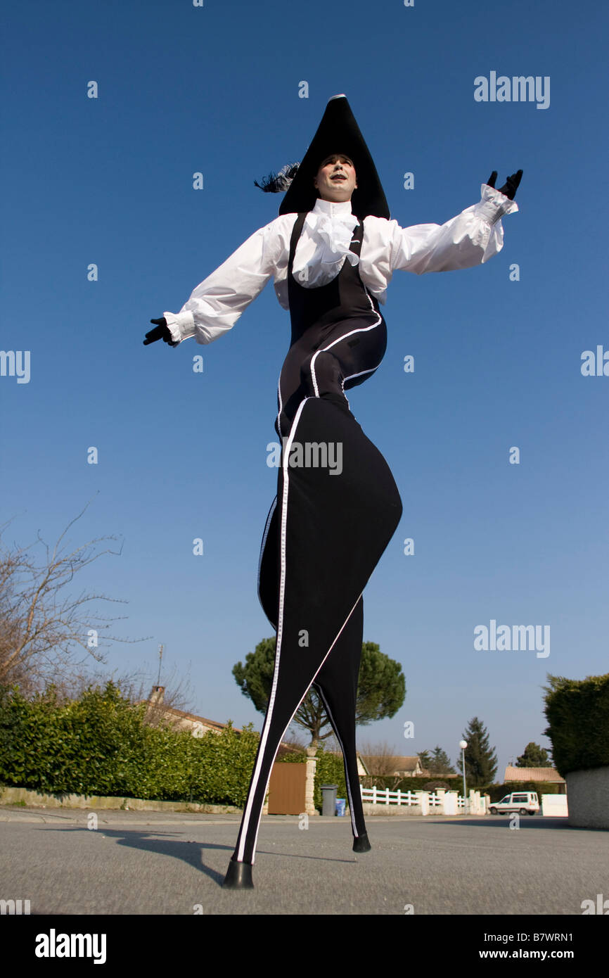 actor dressed as mousquetaire costume on stilts with black hat and