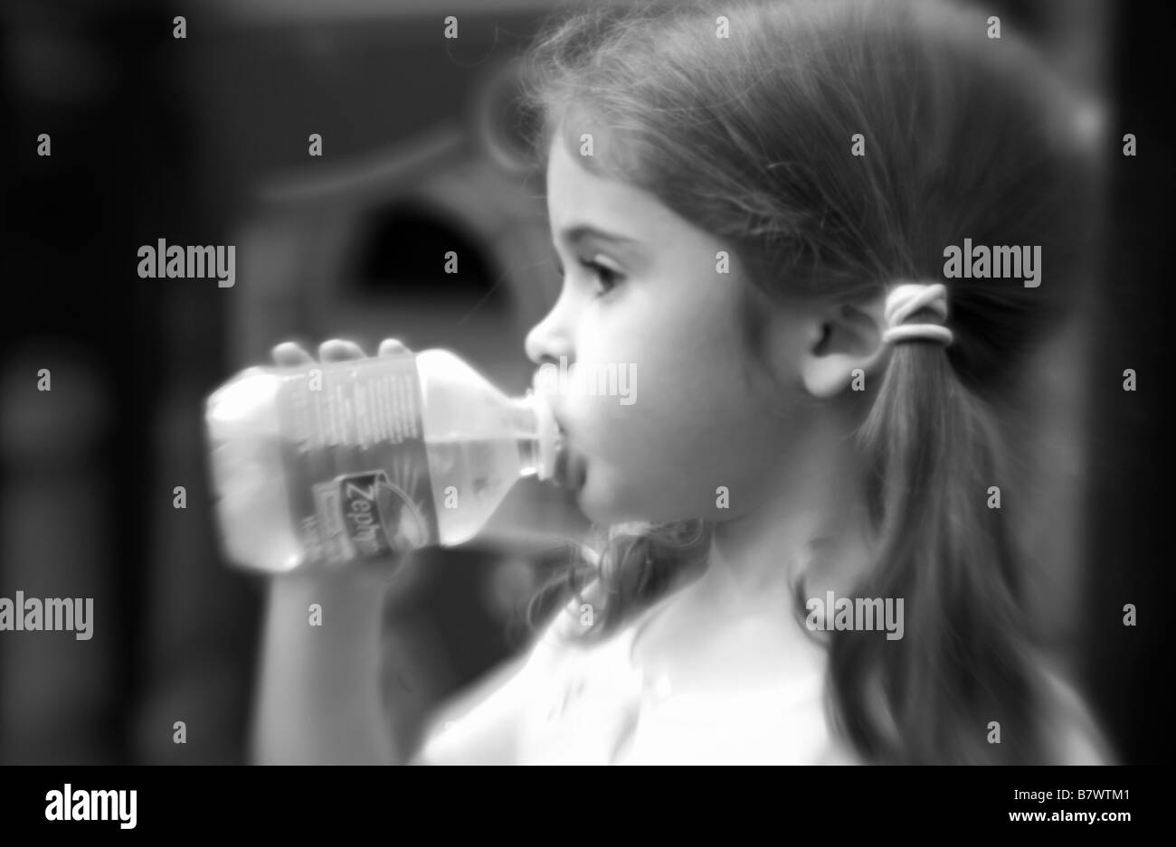 little girl drinking out of a small bottle of water Stock Photo
