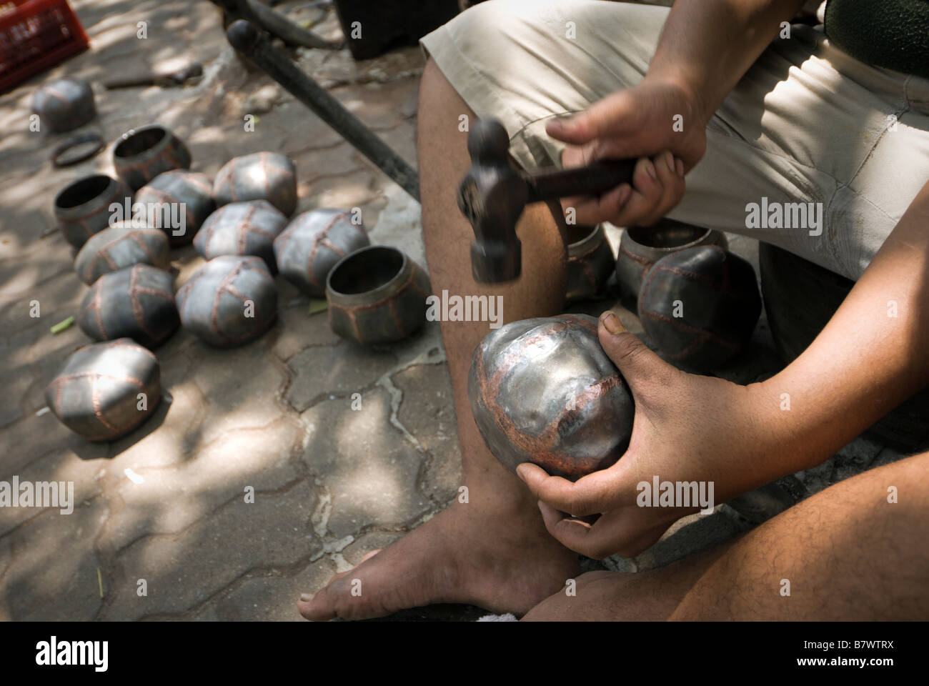 Detail of artisan beating out alms bowls in Monks Bowl Village Soi Ban Baat in central Bangkok Thailand Stock Photo