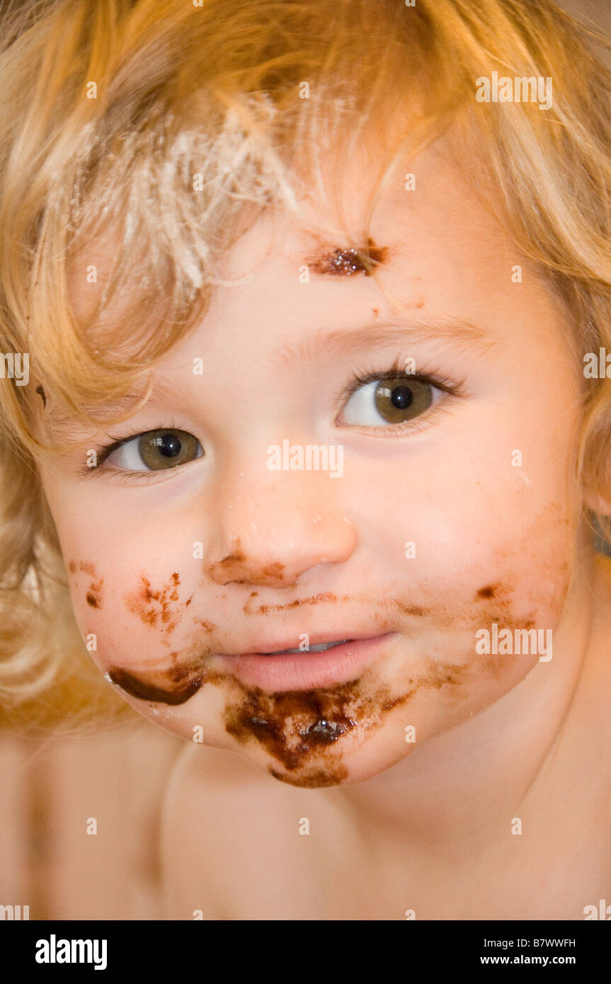 Young girl (2-3) with chocolate covered face after making a cake Stock Photo