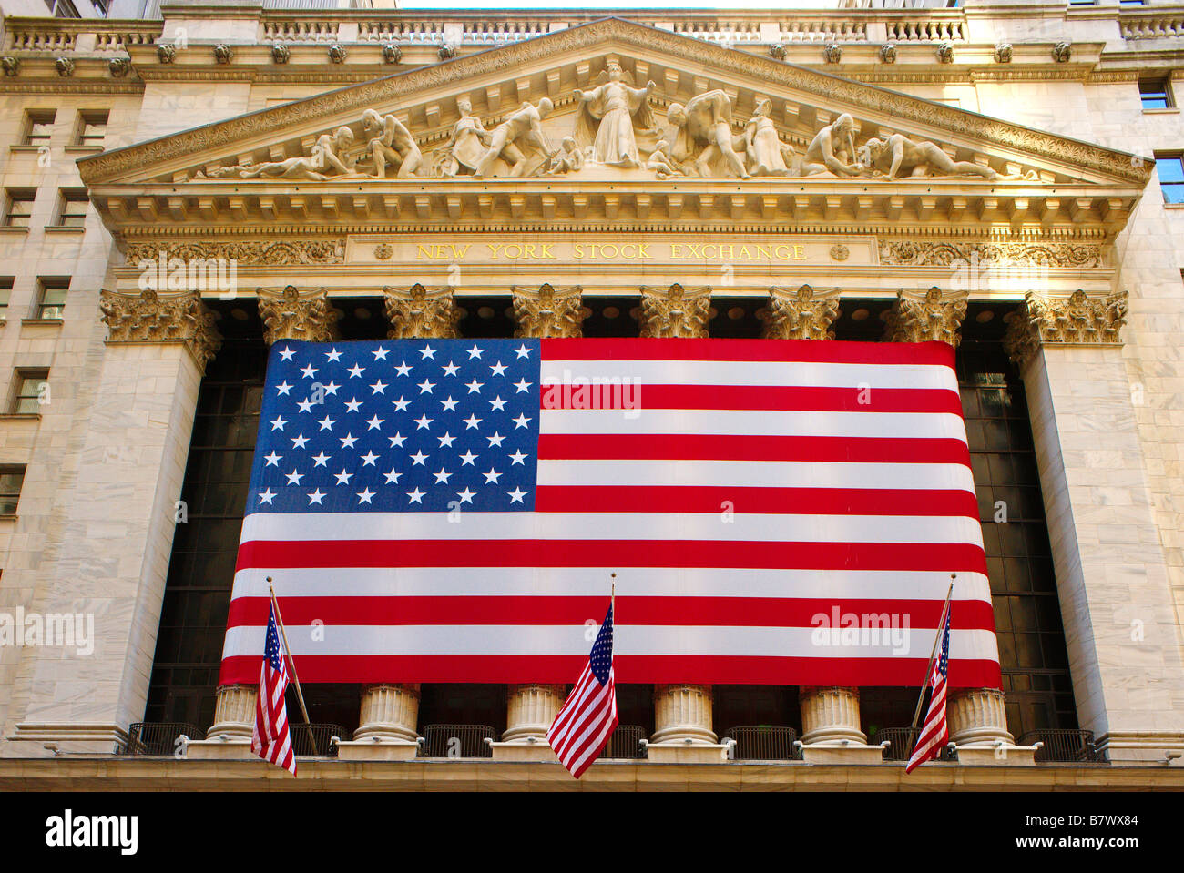 Stars & Stripes USA flag banner across frontage of New York Stock Exchange Stock Photo