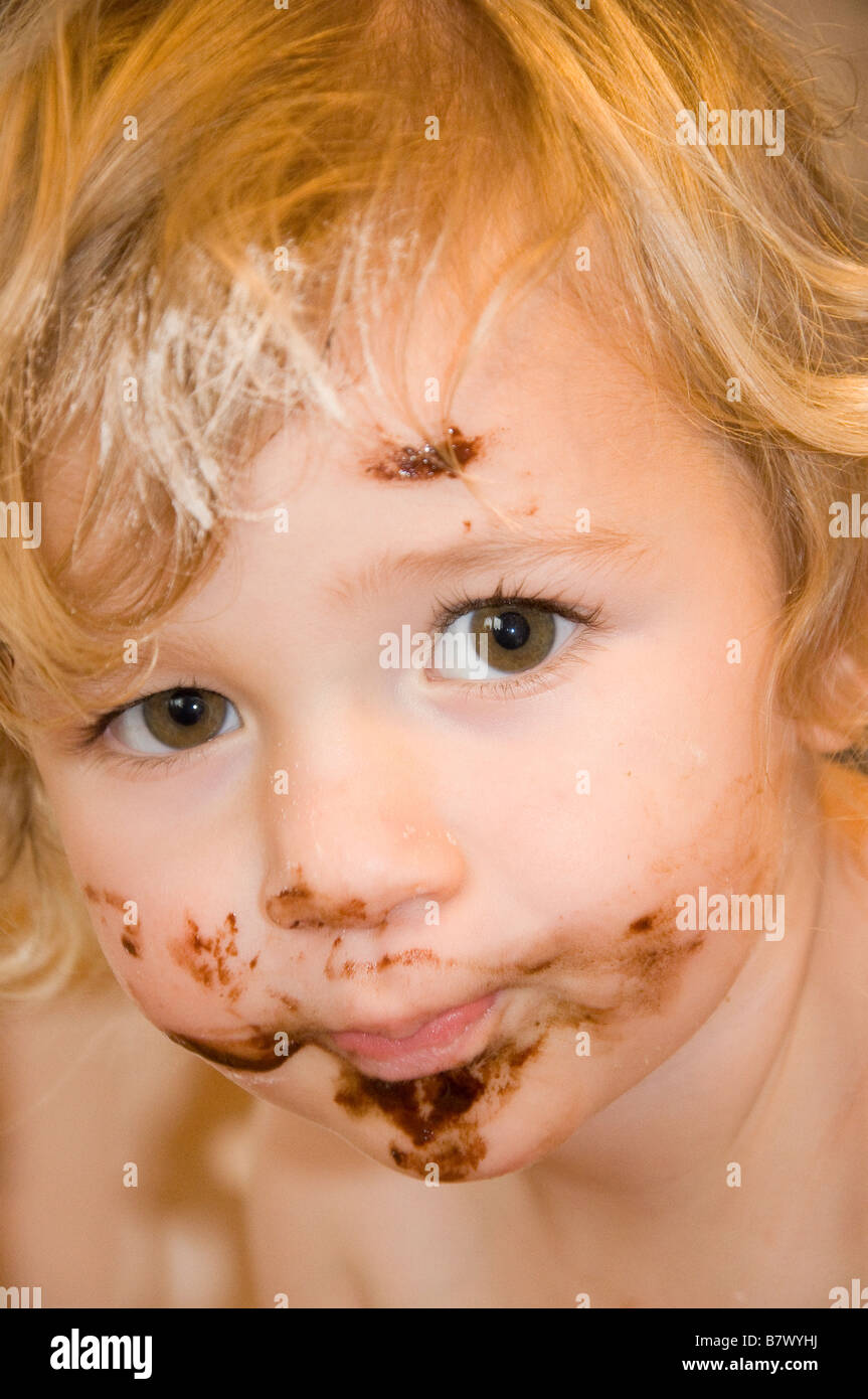 Young girl (2-3) with chocolate covered face after making a cake looking at camera Stock Photo