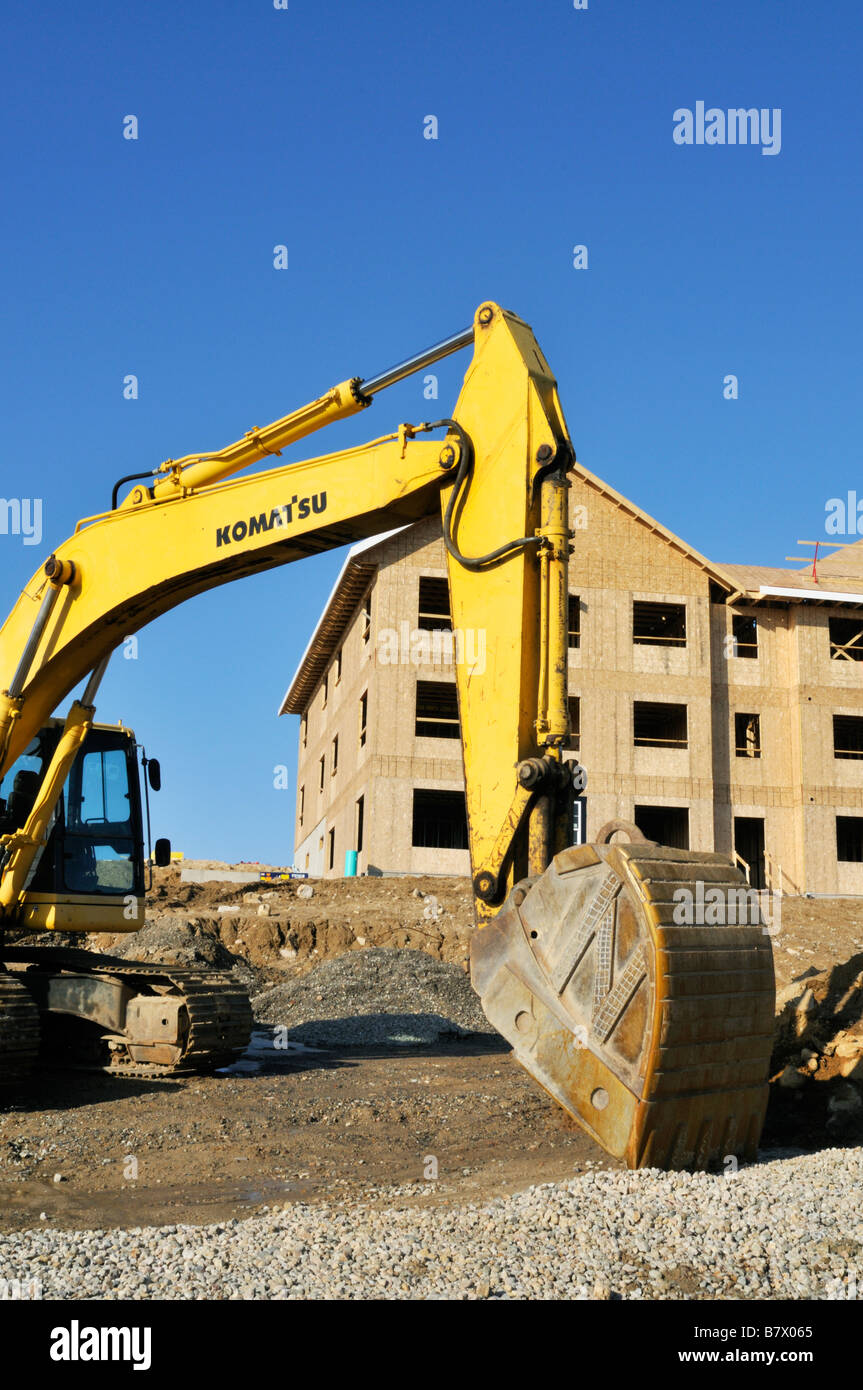 Komatsu excavator crawler at construction site with wood frame apartment building being built on Cape Cod, Massachusetts USA Stock Photo
