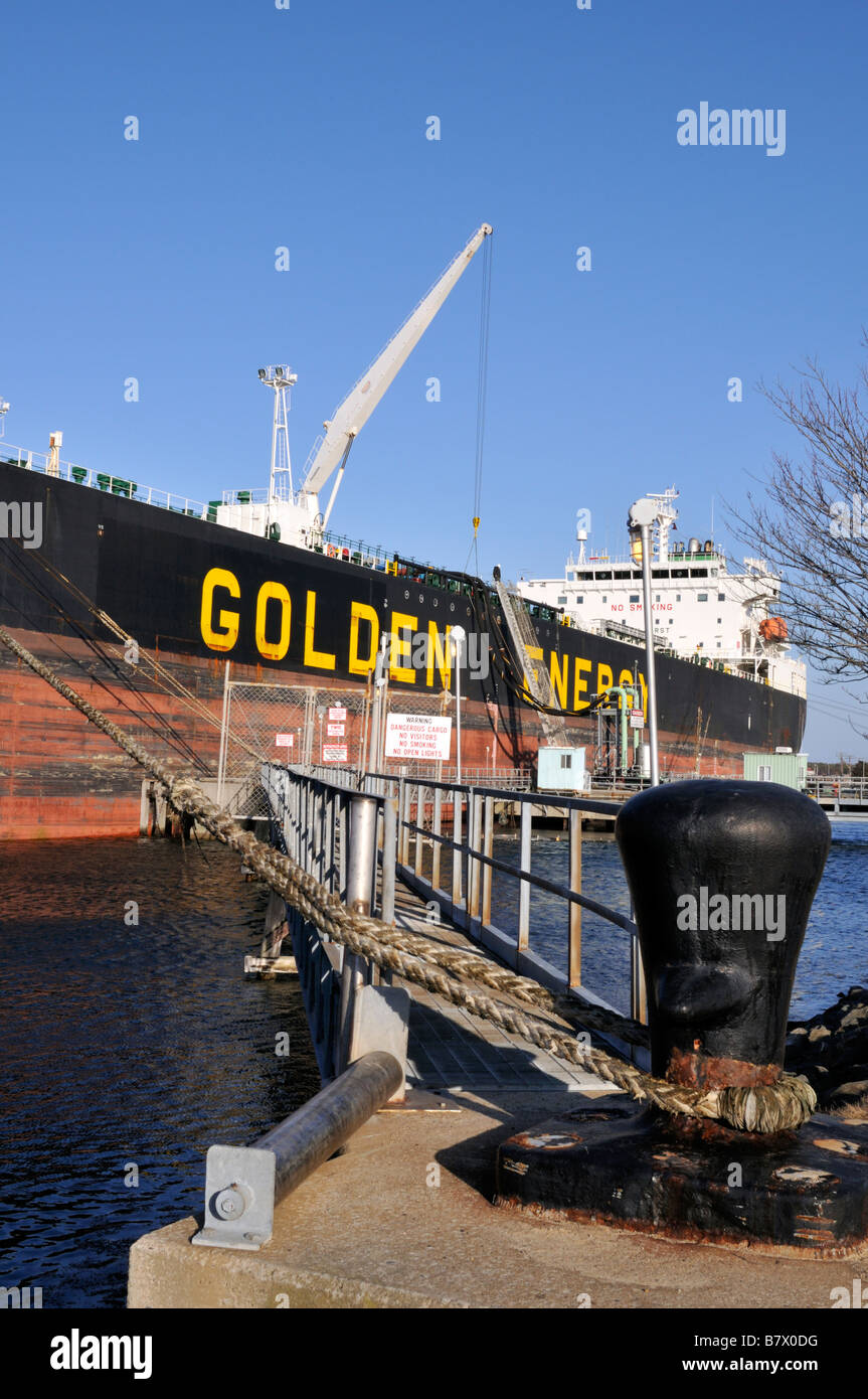 [Fuel tanker] docked at pier showing hose handling crane for offloading oil and docklines secured to bollard Stock Photo