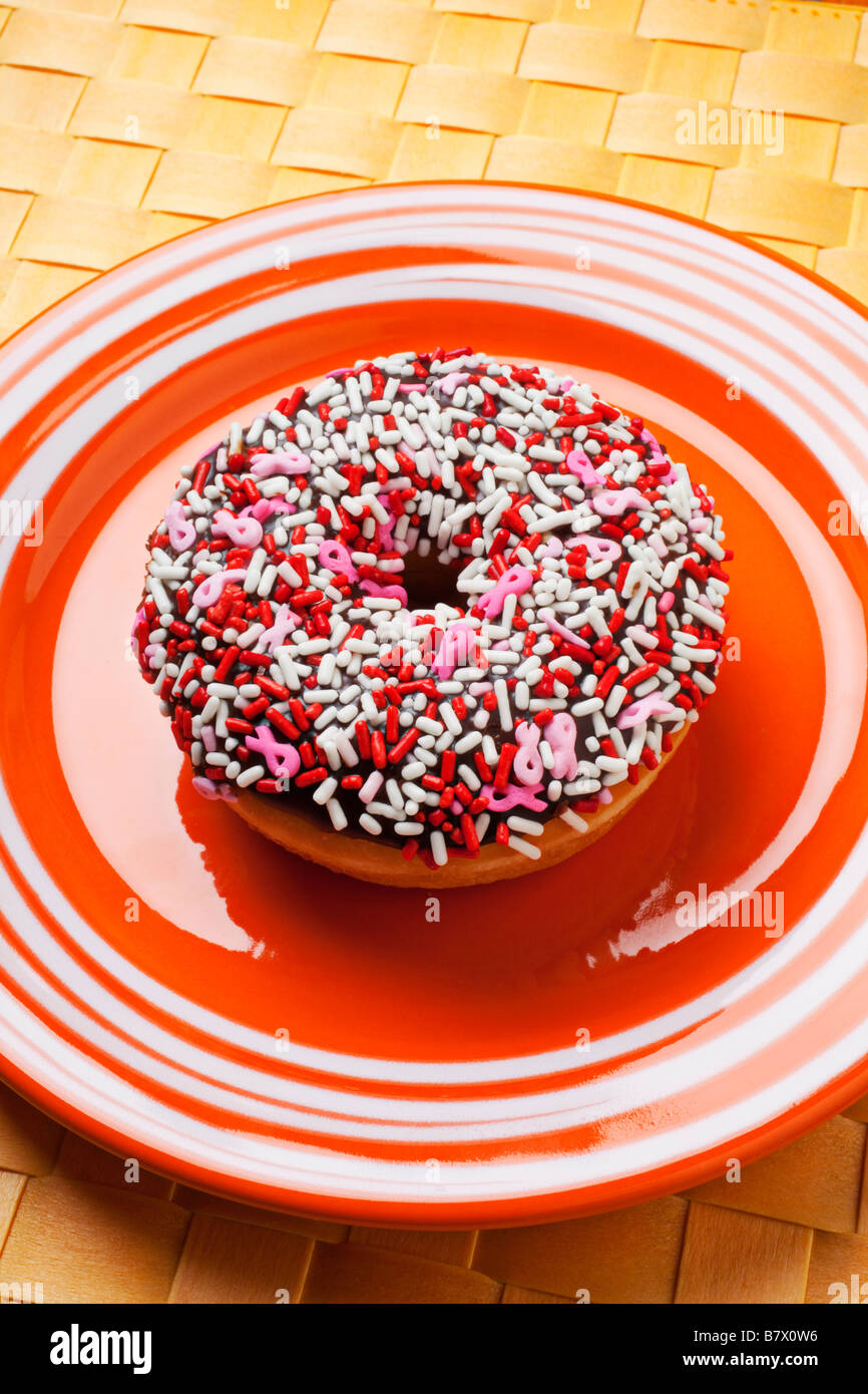 Donut with sprinkles on orange plate Stock Photo
