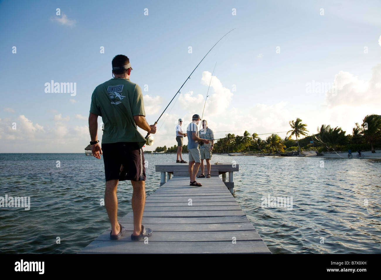 BELIZE Ambergris Caye Four adult males practice flyfishing from dock