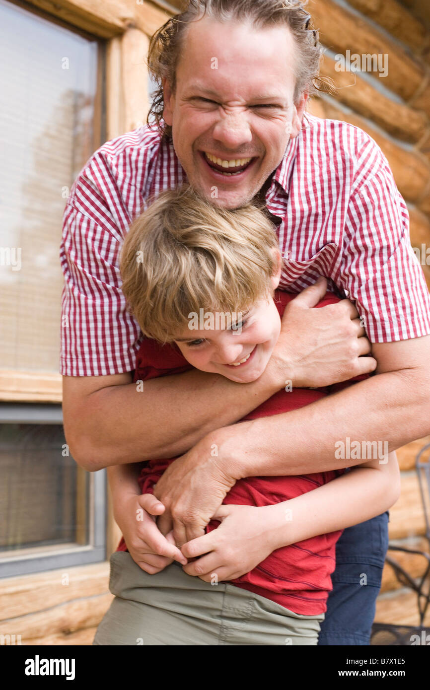 father's day, dad hugging eight year old boy outdoors and smiling Stock Photo