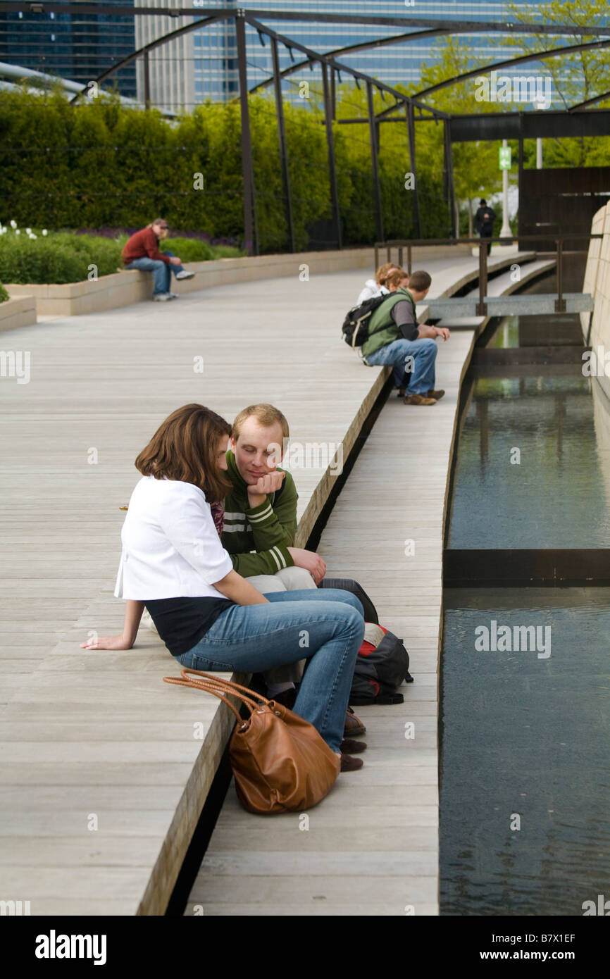 ILLINOIS Chicago People sit by hardwood footbridge and stream that divides Lurie Garden in Millennium Park Stock Photo