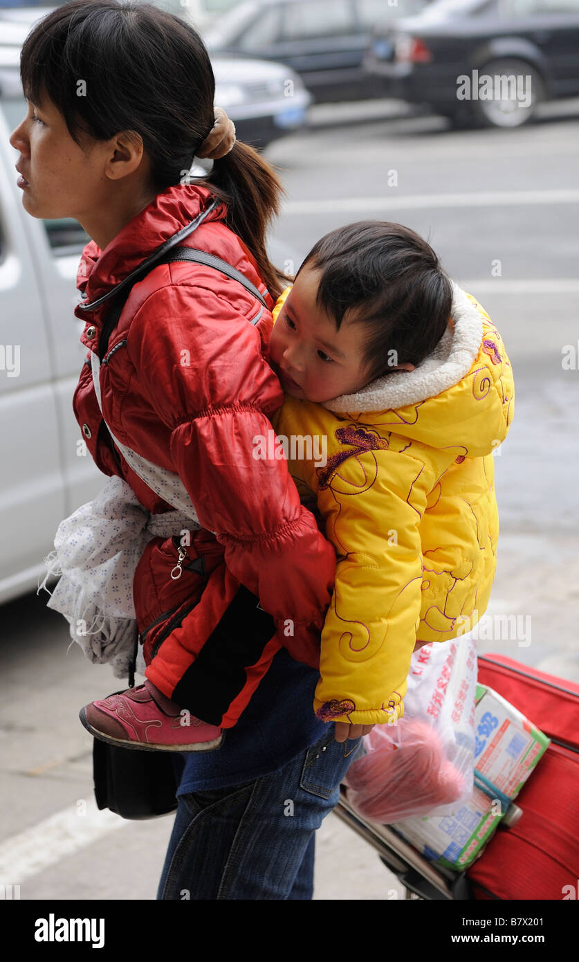 Chinese migrant woman carrying her baby on her back at the train ...