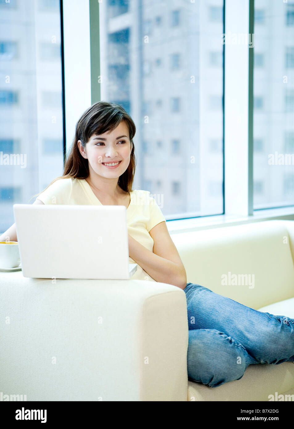 Young woman sitting on sofa with laptop Stock Photo - Alamy