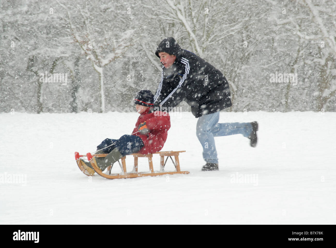 Winter fun Man pushing a young boy on a sledge in the snow, Cheam