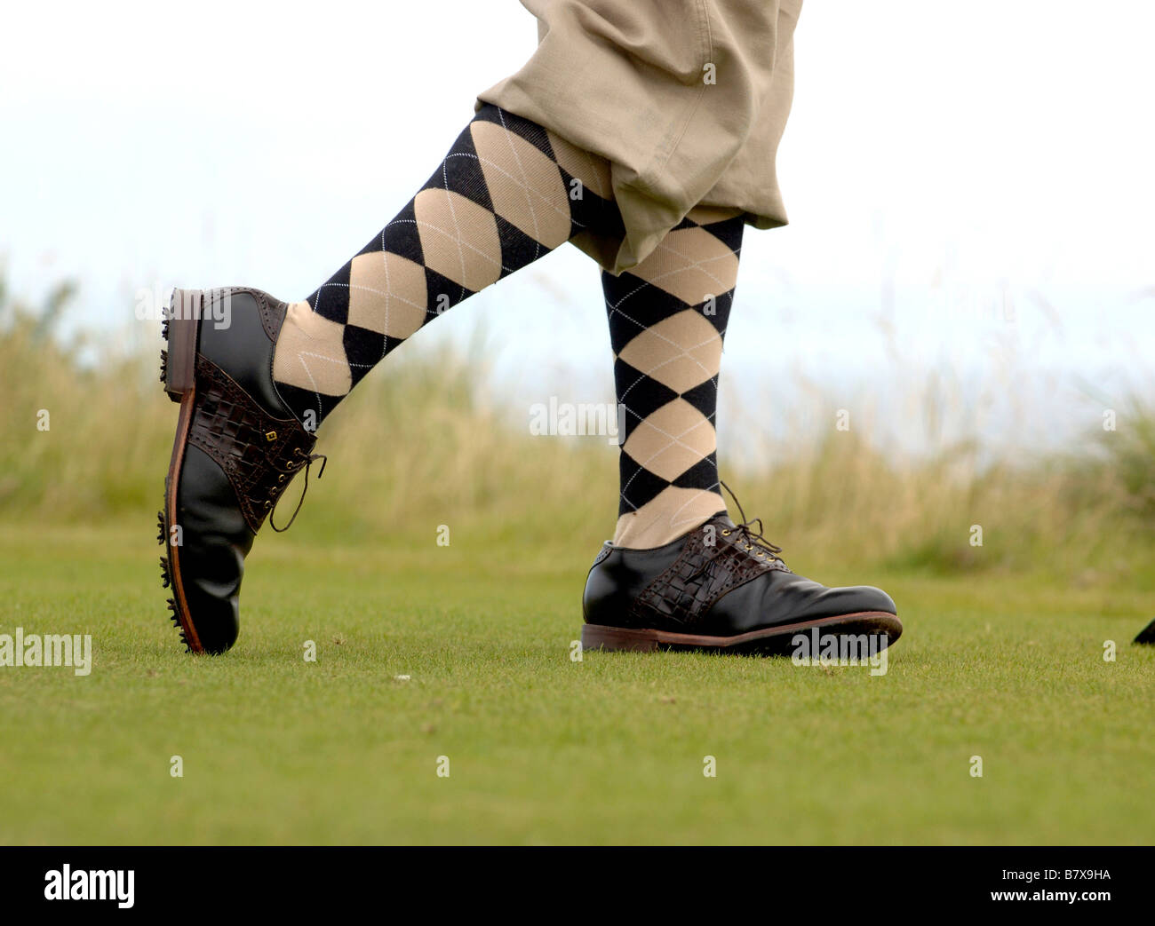 Man gets ready to strike a golf ball wearing plus fours Stock Photo