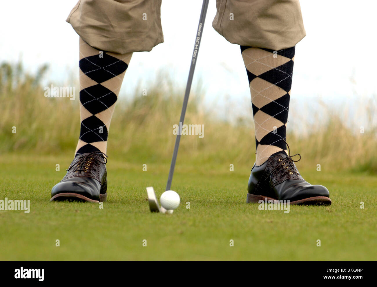 Man gets ready to strike a golf ball wearing plus fours Stock Photo
