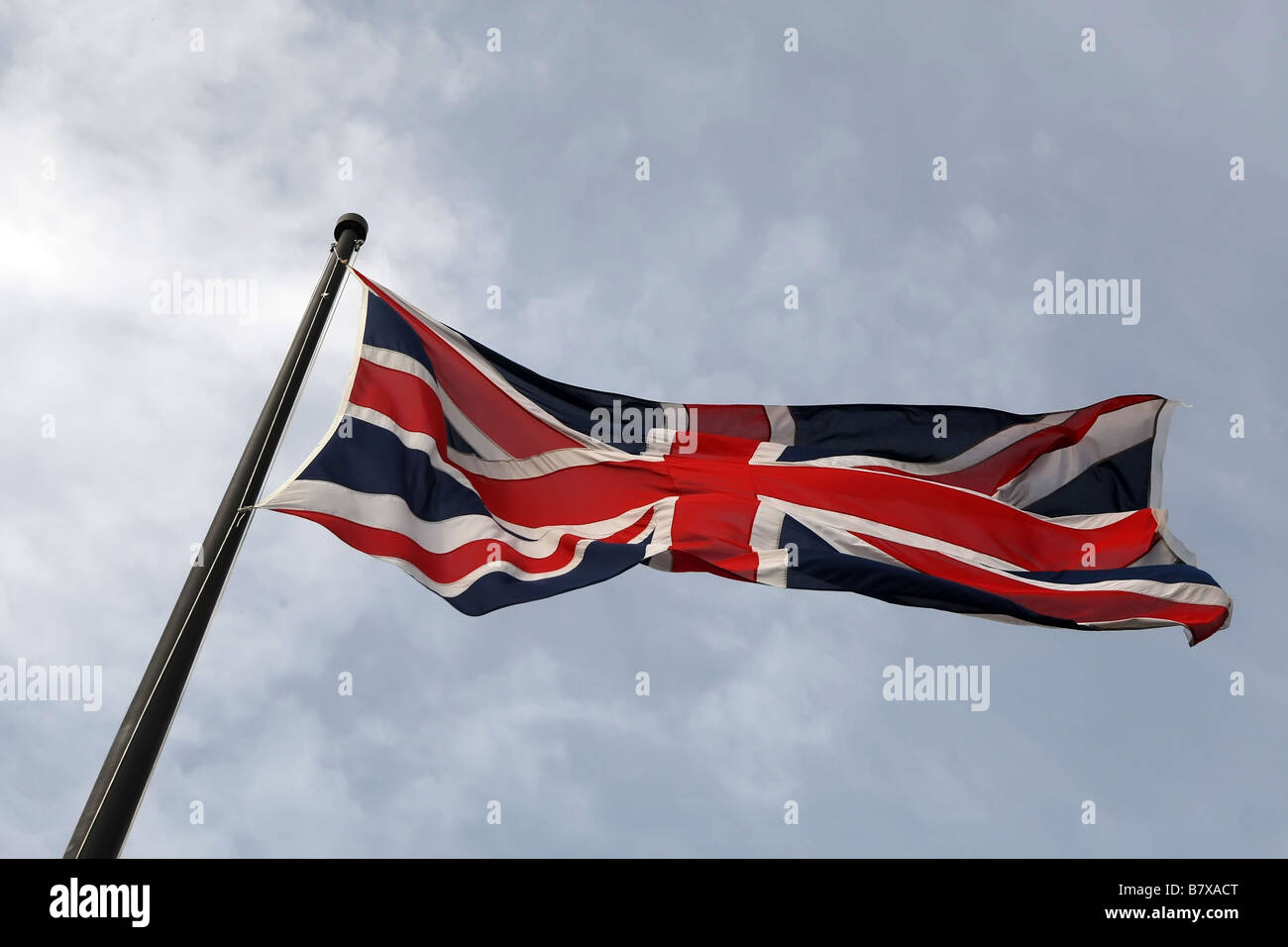The Union Jack (flag), the flag of the United Kingdom, fully flying against a blue sky with some slight cloud. Stock Photo