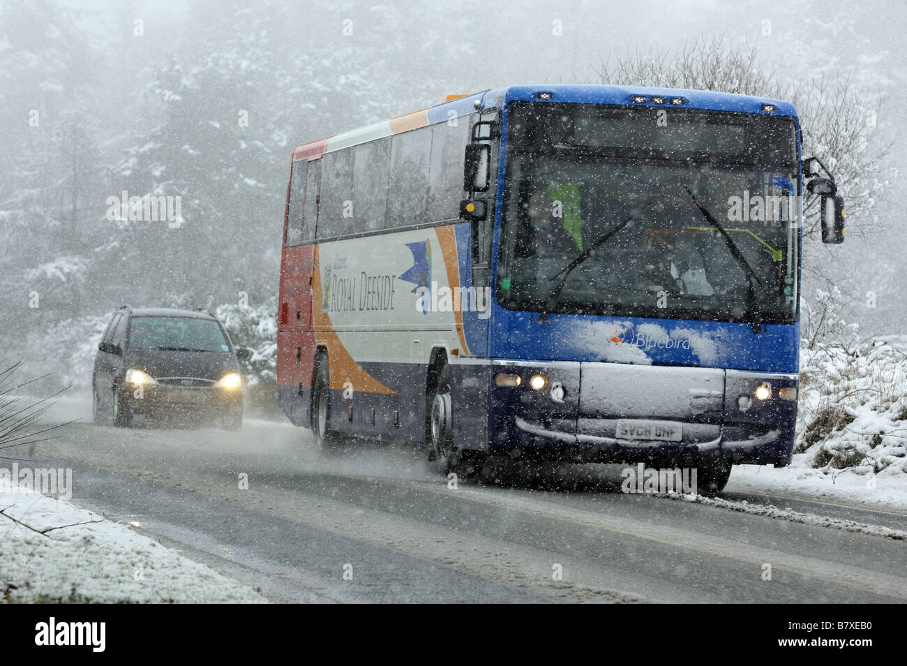 Stagecoach Bluebird bus driving along snow covered road in Rural Aberdeenshire, Scotland, UK Stock Photo