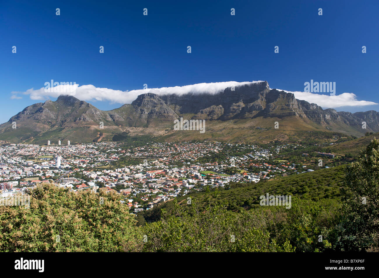 View of the city of Cape Town surrounded by Table Mountain on which the clouds create the well-known 'table cloth' effect. Stock Photo