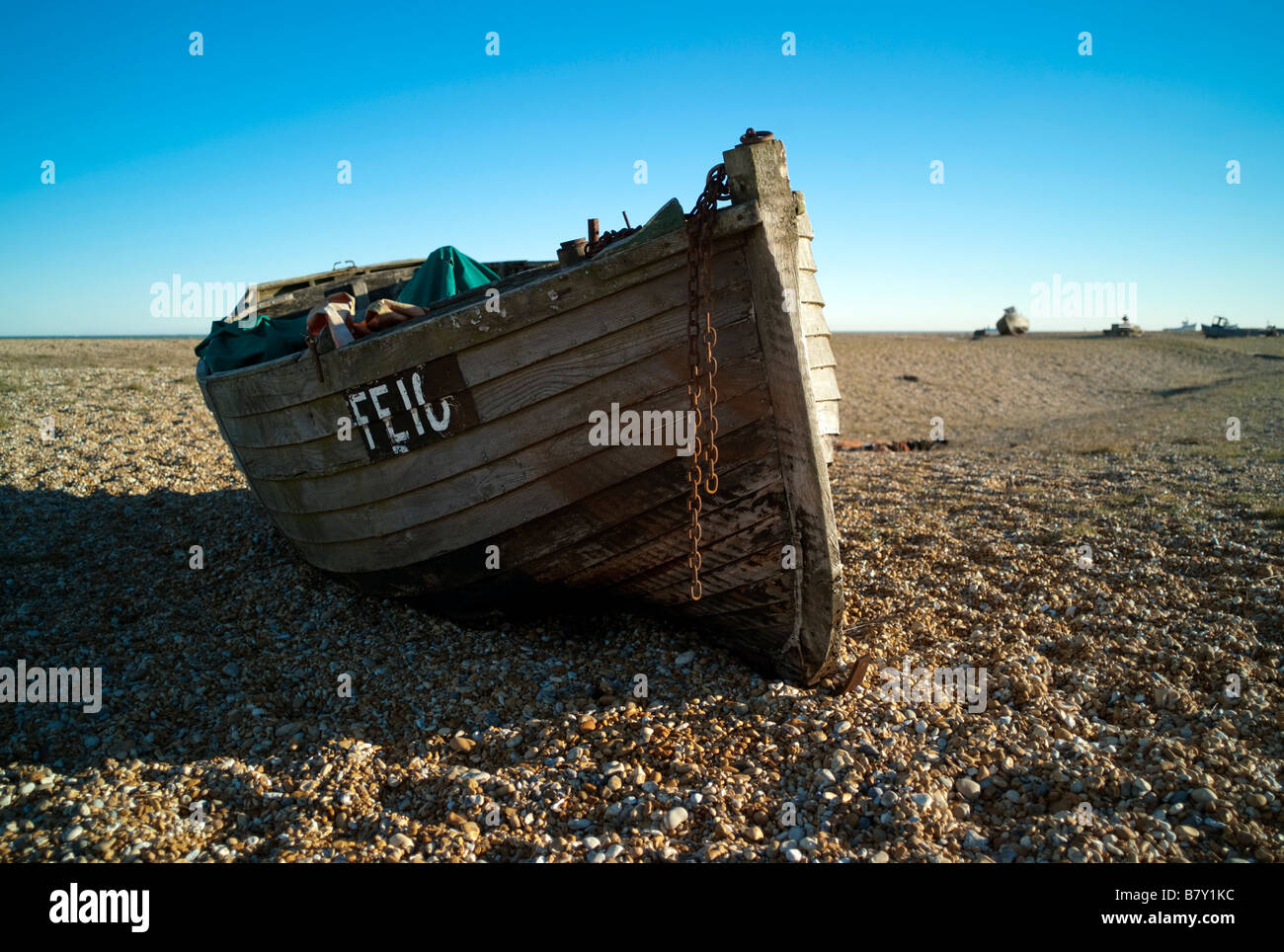 An old abandoned fishing boat drawn up onto a shingle beach on England ...